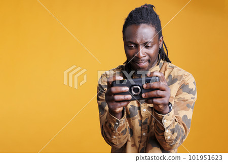 Gamer having fun playing video games on mobile phone, trying to win online gaming competiton. African american man enjoying smartphone videogames in studio over yellow background Gamer having fun playing video games on mobile phone, trying to win online gaming competiton. African american man enjoying smartphone videogames in studio over yellow background 101951623
