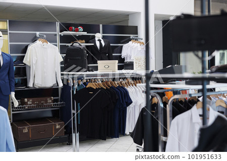 Interior of modern boutique with new collection on hangers, stylish brand design and formal wear in fashionable showroom. Empty clothing store with trendy accessories, commercial activity. Interior of modern boutique with new collection on hangers, stylish brand design and formal wear in fashionable showroom. Empty clothing store with trendy accessories, commercial activity. 101951633