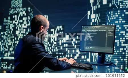 Businessman working on computer in skyscraper office, checking information on monitor in department space. Corporate employee sitting at desk in high end building, urban city lights. Businessman working on computer in skyscraper office, checking information on monitor in department space. Corporate employee sitting at desk in high end building, urban city lights. 101951652