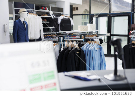 Modern boutique filled with formal wear, multiple racks with fashionable merchandise and trendy accessories. Interior of empty clothing store with stylish shirts on hangers, small business concept. Modern boutique filled with formal wear, multiple racks with fashionable merchandise and trendy accessories. Interior of empty clothing store with stylish shirts on hangers, small business concept. 101951653