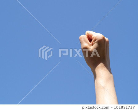A fist raised towards the clear blue sky. A fist raised towards the clear blue sky. 101951737