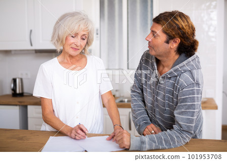 Aged woman and man sign documents sitting in room interior 101953708