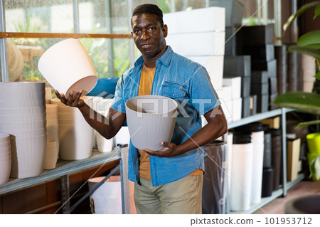 Smiling african american florist looking for flowerpots in garden supplies warehouse 101953712