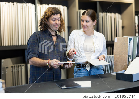 Man and woman together choosing bathroom tile patterns in hardware store 101953714