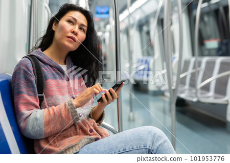 Woman with suitcase and sitting on bench in subway train and using smartphone 101953776