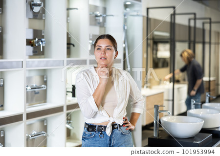 Confident female customer looking around in bathroom section of hardware store Confident female customer looking around in bathroom section of hardware store 101953994