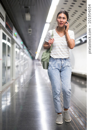 Oriental woman having telephone conversation in subway station Oriental woman having telephone conversation in subway station 101954054