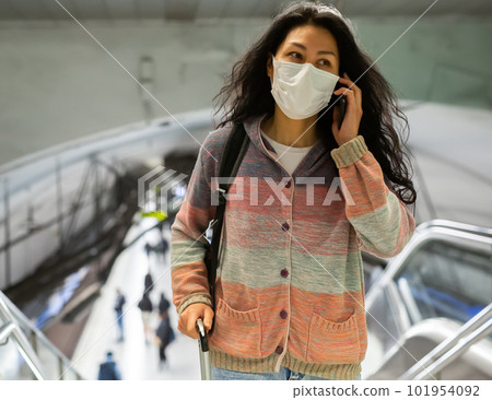 Woman in face mask with backpack walking in subway beside escolator Woman in face mask with backpack walking in subway beside escolator 101954092