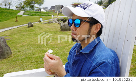 A man eating soft serve ice cream in the park A man eating soft serve ice cream in the park 101955223