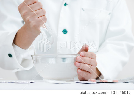 有粉碎說明的藥劑師。一隻手在杵中混合藥物 有粉碎說明的藥劑師。一隻手在杵中混合藥物 101956012