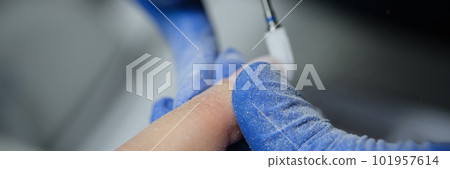 Manicurist in gloves doing hardware manicure to client using special apparatus Manicurist in gloves doing hardware manicure to client using special apparatus 101957614