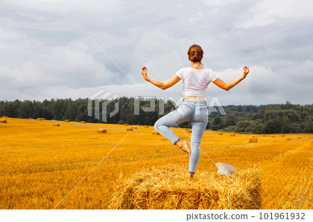 girl with straw hat stands on a haystack on a bale in the agricultural field after harvesting girl with straw hat stands on a haystack on a bale in the agricultural field after harvesting 101961932