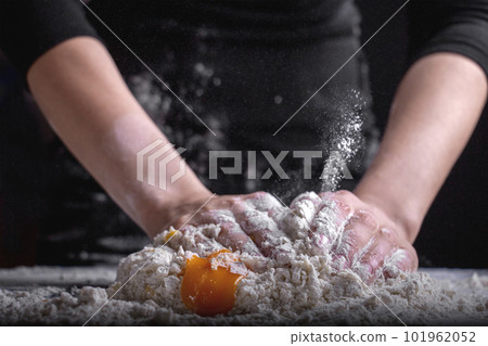 A chef is kneading dough using eggs, kitchen dark background A chef is kneading dough using eggs, kitchen dark background 101962052