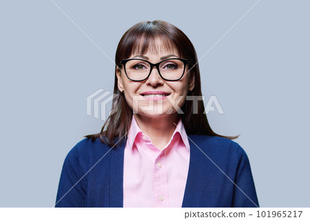 Close-up portrait of middle aged woman on grey studio background Close-up portrait of middle aged woman on grey studio background 101965217