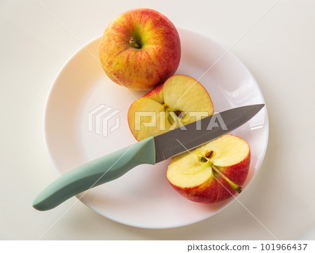 Ripe red apples in plate with a knife. Cut an Apple before eating to follow diet or fasting days 101966437