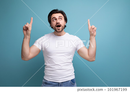 indignant stylish brutal brunette man in a white t-shirt points his finger to the side 101967199