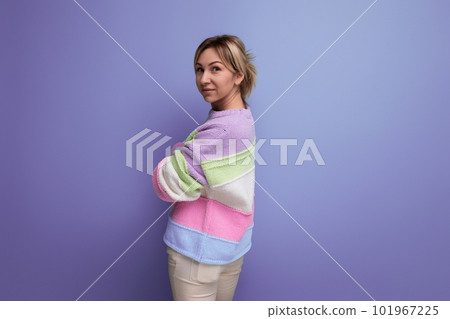 attractive blond young woman standing sideways on purple background with copy space 101967225