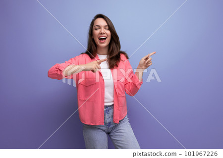 smart brunette lady casual style pointing finger at space for information on studio background 101967226