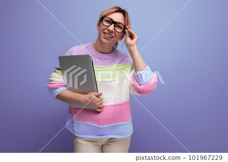 blond female student with a laptop in her hands adjusts her glasses on a purple background blond female student with a laptop in her hands adjusts her glasses on a purple background 101967229