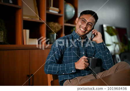 Successful Asian businessman talking on the phone with his business partner in his office. Successful Asian businessman talking on the phone with his business partner in his office. 101968436