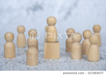 A wooden figure on top of wooden block representing a leader surrounded by other wooden figure. Leadership concept. A wooden figure on top of wooden block representing a leader surrounded by other wooden figure. Leadership concept. 101969037