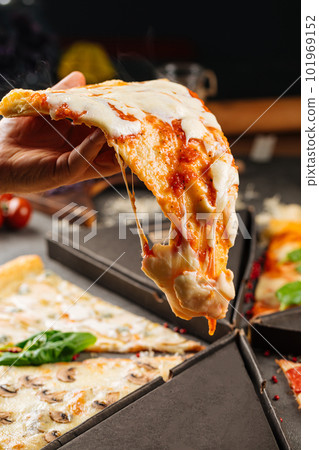 Holding slice of pizza with dripping cheese Holding slice of pizza with dripping cheese 101969152