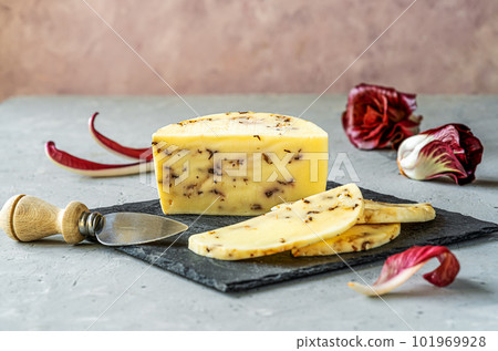 Italian traditional soft cheese Caciotta with radicchio cut on black stone board, grey and rose background, fresh radish, cheese knife Italian traditional soft cheese Caciotta with radicchio cut on black stone board, grey and rose background, fresh radish, cheese knife 101969928
