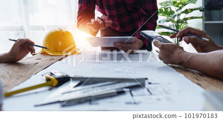 Architect and Engineer working with blueprints for architectural plan, engineer sketching a construction project, green energy concept 101970183