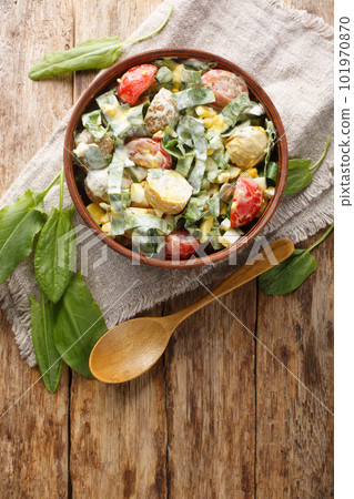 Fresh salad of eggs, potatoes, tomatoes and sorrel seasoned with cream sauce close-up in a bowl. Vertical top view 101970870