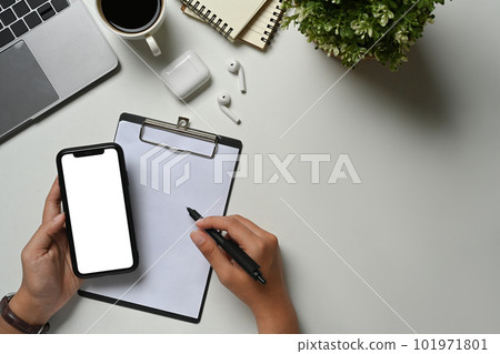 Above view of manumitting at workplace and using mobile phone. Blank screen for advertising text message Above view of manumitting at workplace and using mobile phone. Blank screen for advertising text message 101971801