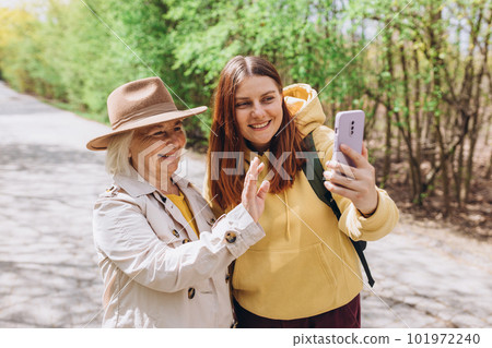 Two women together wear casual clothes doing selfie shot pov on mobile cell phone. Family day concept. Young woman and senior middle aged mom spending time together 101972240