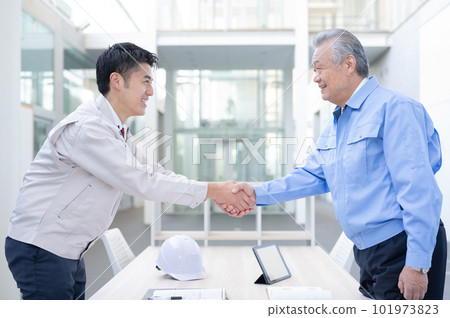 Men in work clothes shaking hands 101973823