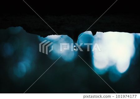 Small water drop with reflection of a forest on icicle formed on the edge of the wall window with visible blurred forest on the background in evening twilight Small water drop with reflection of a forest on icicle formed on the edge of the wall window with visible blurred forest on the background in evening twilight 101974177
