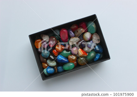 Bunch of raw semi-precious colored quartz stones in a black box top view 101975900