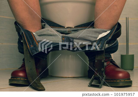 A man sitting on the toilet. A concept from the 1980s. Red punk shoes and jeans A man sitting on the toilet. A concept from the 1980s. Red punk shoes and jeans 101975957