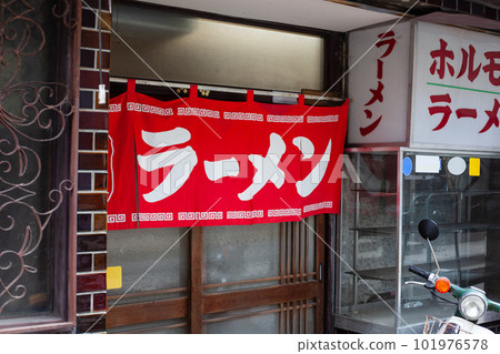 拉麵店的外牆掛著紅色的窗簾和一輛送貨自行車 拉麵店的外牆掛著紅色的窗簾和一輛送貨自行車 101976578