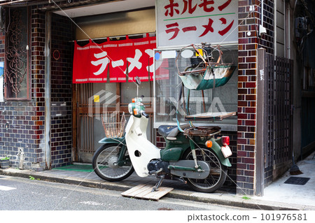 The exterior of a ramen shop with a red curtain and a delivery bike 101976581