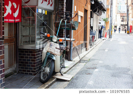 The exterior of a ramen shop with a red curtain and a delivery bike 101976585