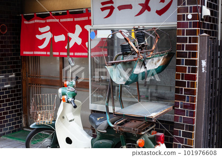 The exterior of a ramen shop with a red curtain and a delivery bike The exterior of a ramen shop with a red curtain and a delivery bike 101976608