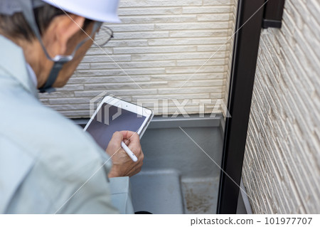 A male worker inspecting the outer wall of the veranda of a detached house A male worker inspecting the outer wall of the veranda of a detached house 101977707