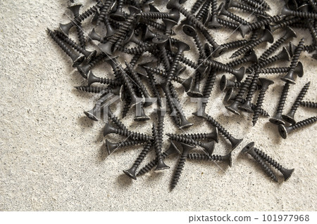 Close-up image of many small black screws on concrete background Close-up image of many small black screws on concrete background 101977968