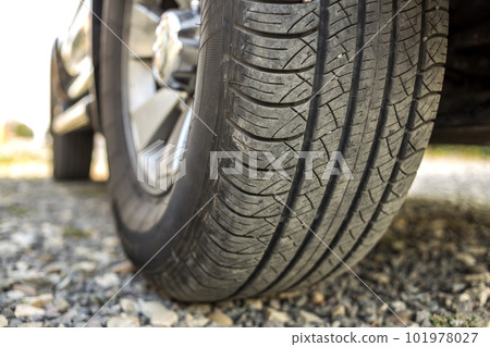 Close-up detail of car wheel with aluminum disc and black rubber tire protector on light blurred outdoors background. Transportation, safety, reliability, modern design concept. Close-up detail of car wheel with aluminum disc and black rubber tire protector on light blurred outdoors background. Transportation, safety, reliability, modern design concept. 101978027