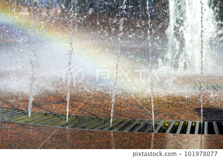 Close up of beautiful city fountain. Splashing upward crystal thin streams of clear cool transparent water, shiny droplets. Multicolored blurred rainbow, recreation area. Close up of beautiful city fountain. Splashing upward crystal thin streams of clear cool transparent water, shiny droplets. Multicolored blurred rainbow, recreation area. 101978077