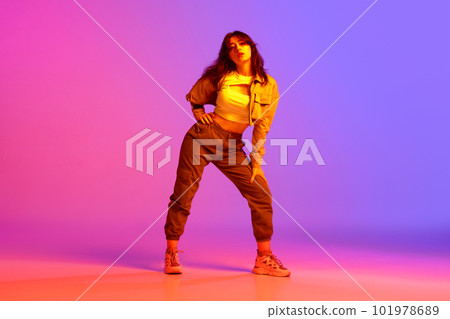 Artistic, beautiful, young girl dancing hip-hop against gradient pink purple background in neon light. Model in casual clothes Artistic, beautiful, young girl dancing hip-hop against gradient pink purple background in neon light. Model in casual clothes 101978689