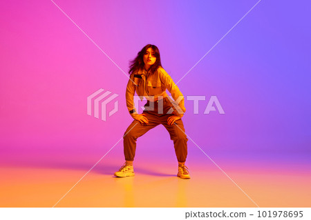 Active, artistic young woman, hip hop dancer in sport style clothes dancing against gradient pink purple background in neon light 101978695