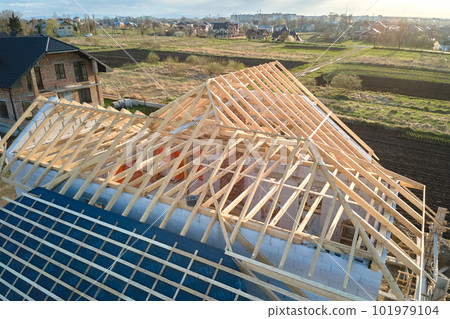 Aerial view of unfinished frame of private house with aerated lightweight concrete walls and wooden roof frame under construction. 101979104