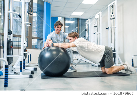 Experienced instructor assisting a man in a rehabilitation workout 101979665