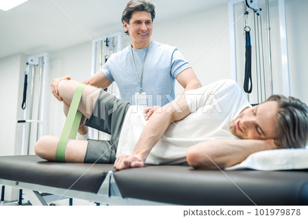 Patient lying on a couch and exercising with a resistance band 101979878