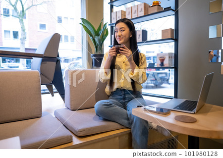 Joyous remote worker whiling away time in a coffeehouse Joyous remote worker whiling away time in a coffeehouse 101980128