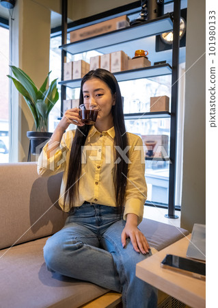 Female sipping a caffeinated beverage in a coffeehouse 101980133